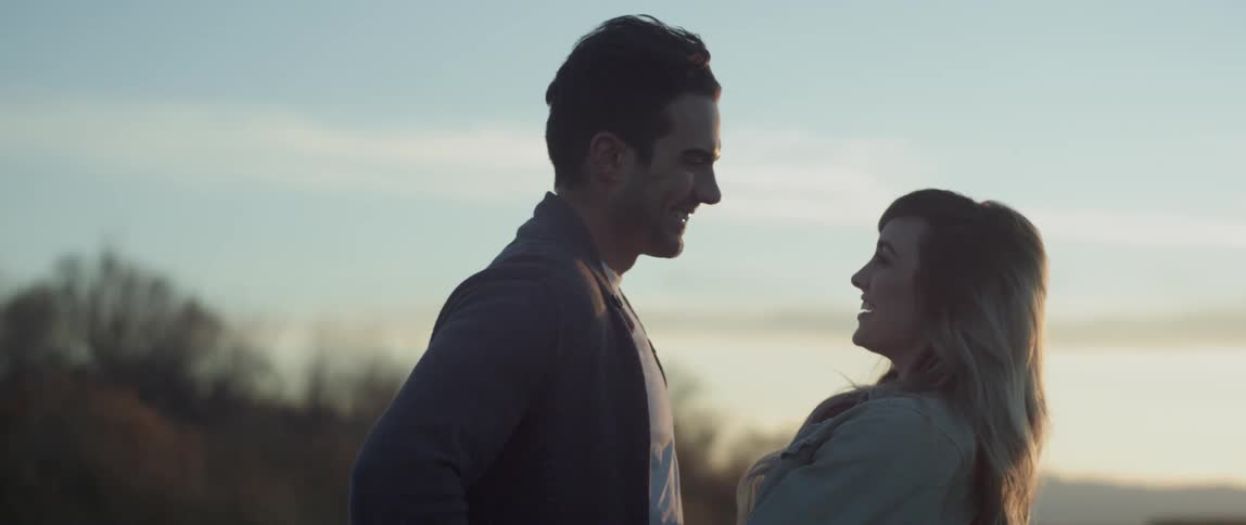 A man and woman hug outside at dusk