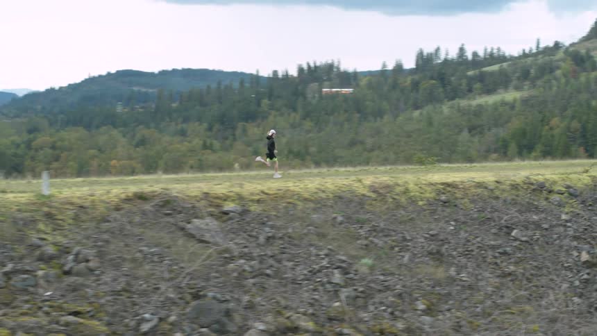 Runner runs along ridge near forest and lake