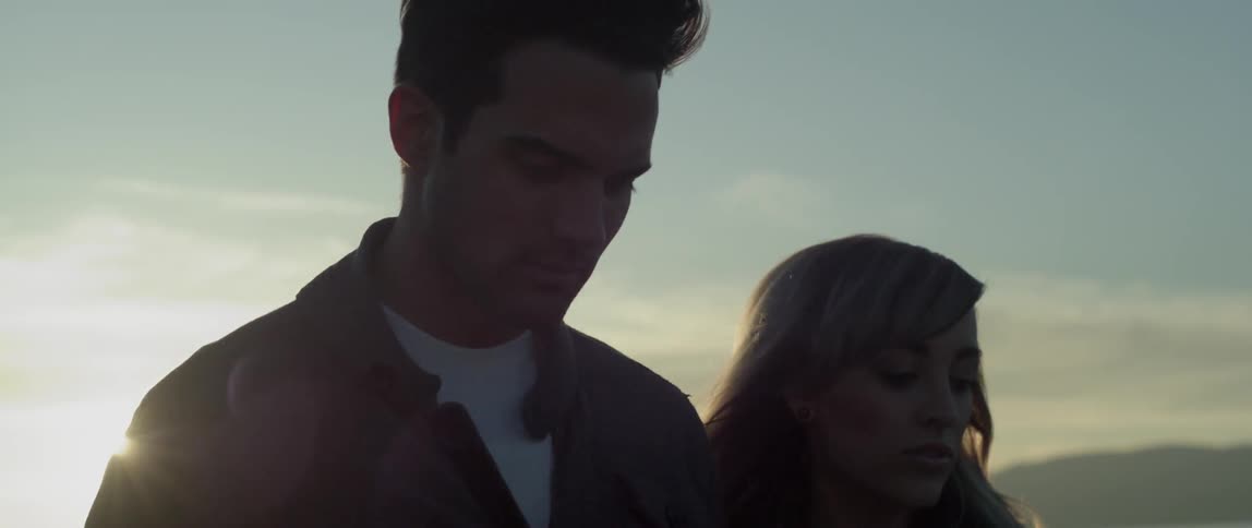A man and woman walk as the sun sets behind them