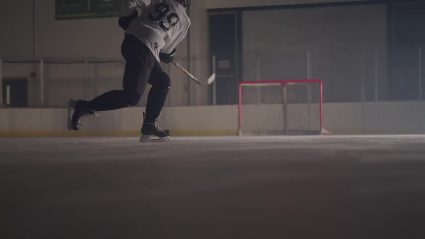 A person smacks a hockey puck across the ice rink