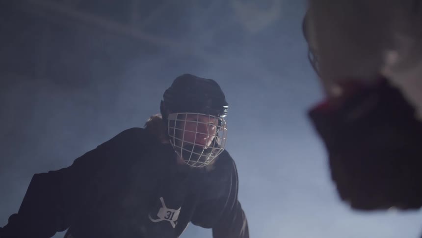Two hockey players face off in dimly lit building