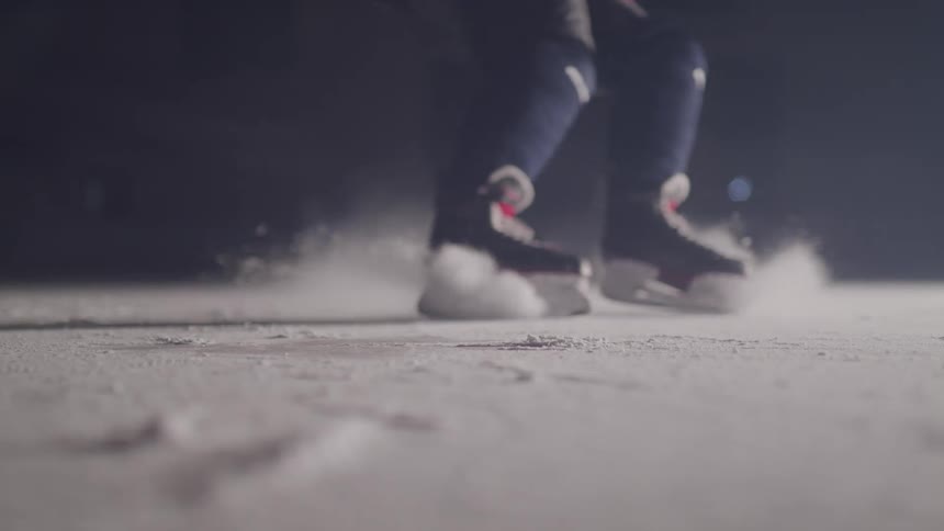 Hockey player skating then stopping and spraying ice indoors