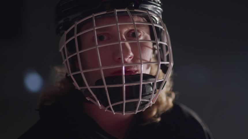 Hockey player stands and looks at the camera in the ice hockey rink