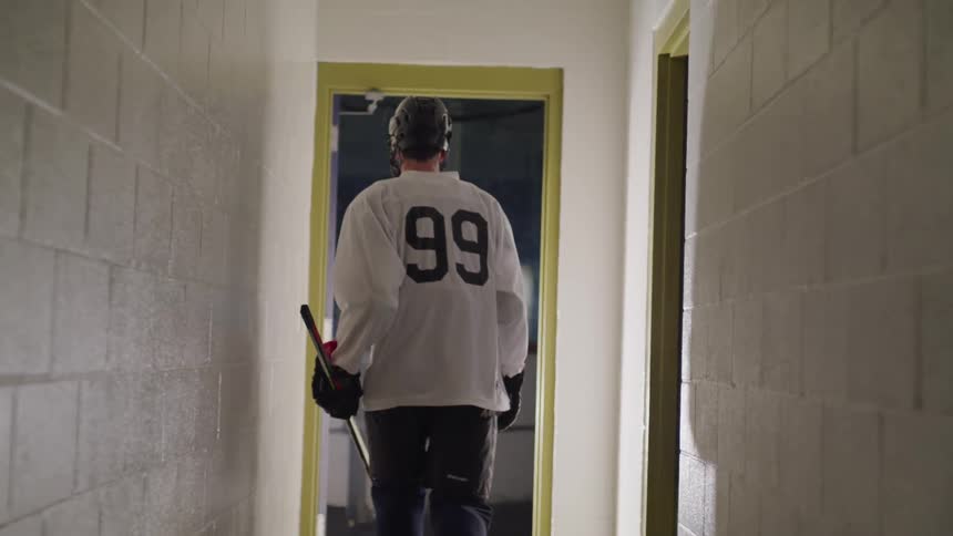 A man with a helmet and a sports uniform walking in a hallway