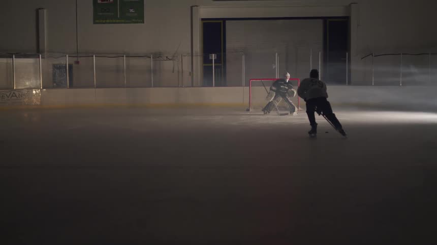 A hockey player skates forward to take a shot at the goal