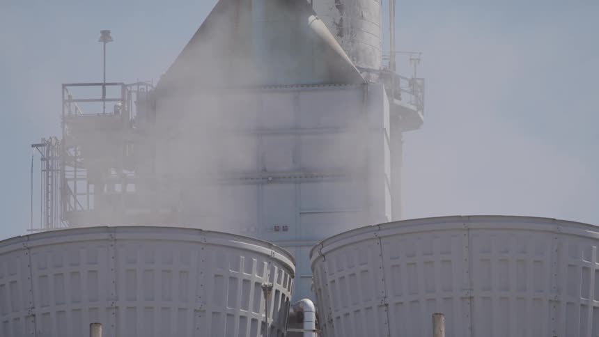 Vapor rises from large cylinders at factory