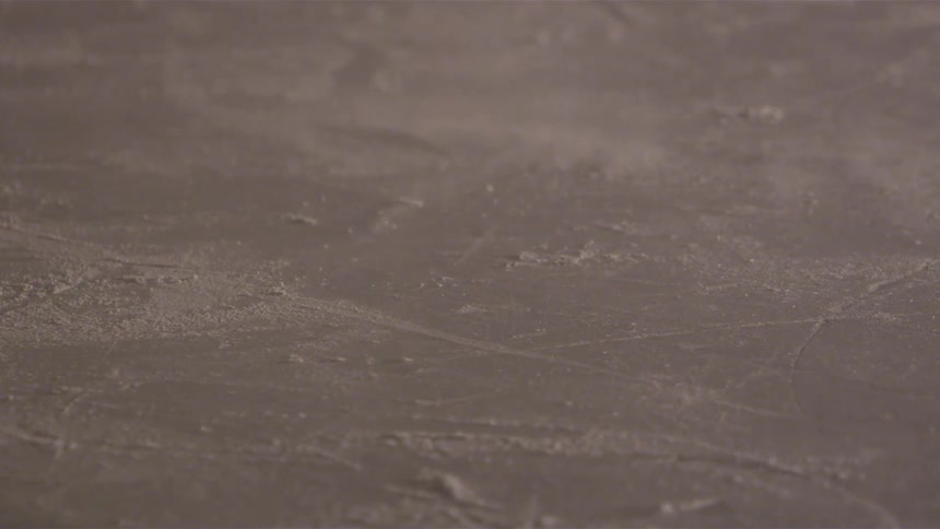 A hockey stick hits a puck in an ice rink