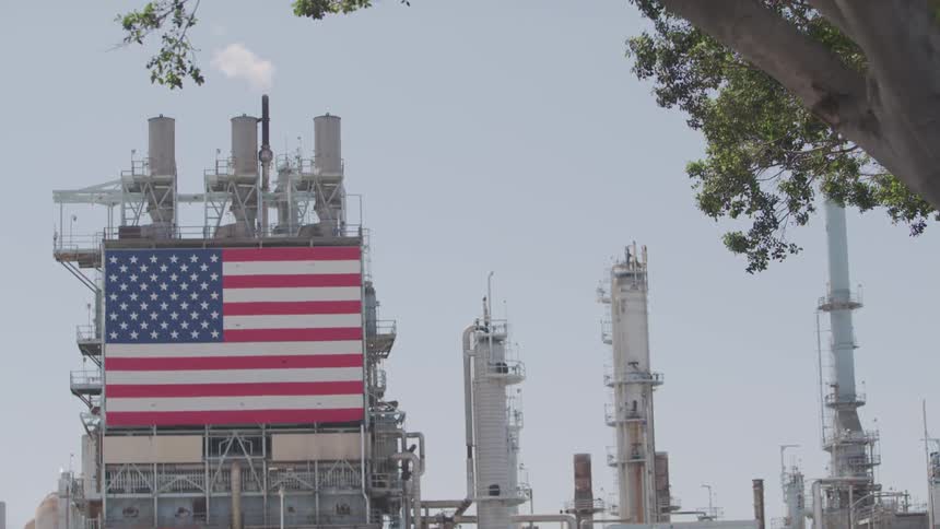 A large american flag hides on the front of a power plant