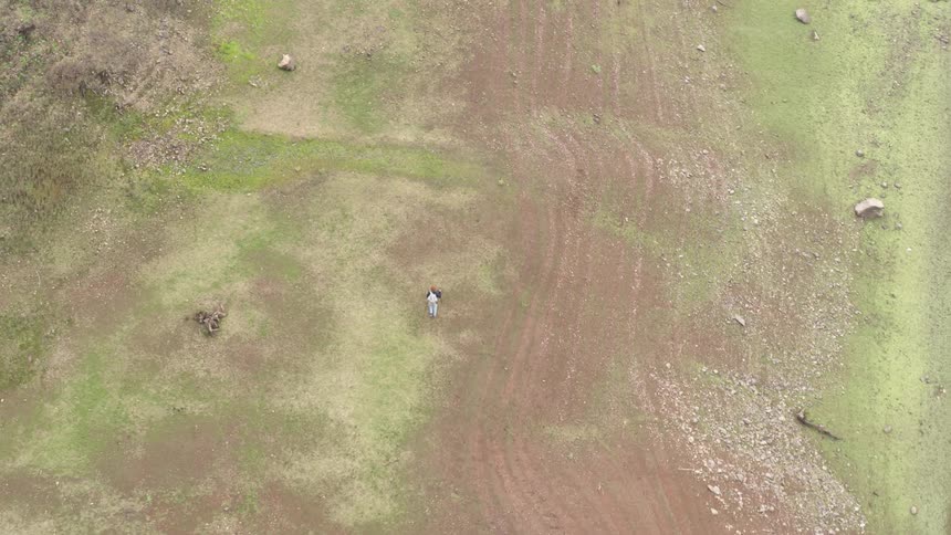 Aerial view of man walking through barren field