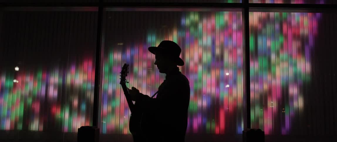 A man is playing a musical instrument in front of a large screen