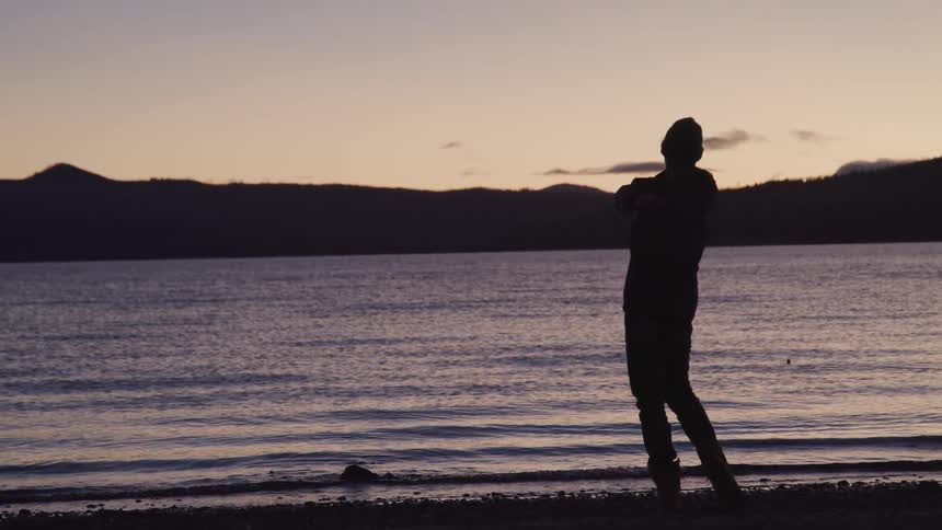 A boy skips a rock in the water