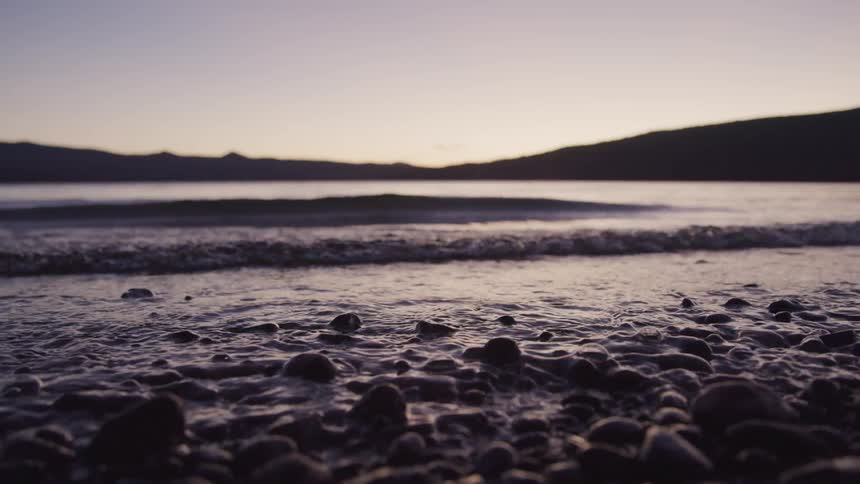 Small lake waves break against the shore at dusk