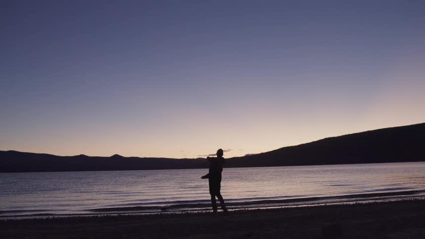 Man throwing rock at a lake at dusk