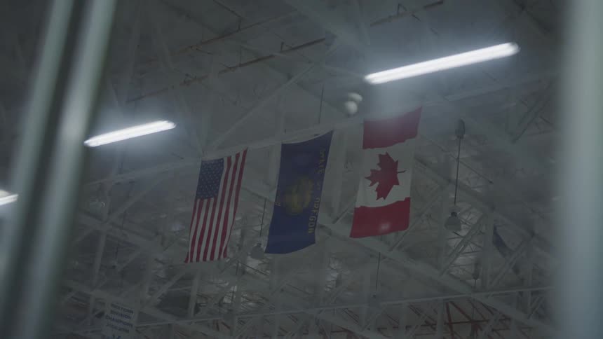 American canadian and division flag hanging from rafters in an ice rink