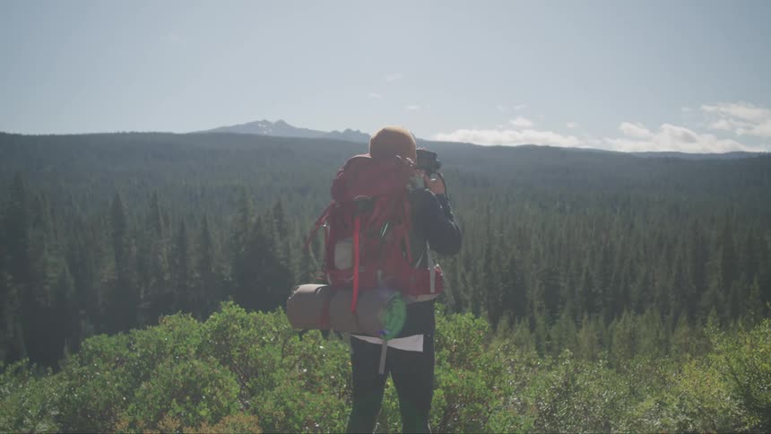 Man filming or taking pictures of the landscape over a huge forest