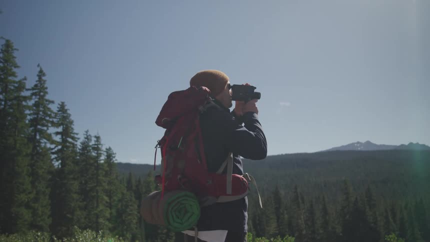 Male photographer makes a video in the forest on a sunny day