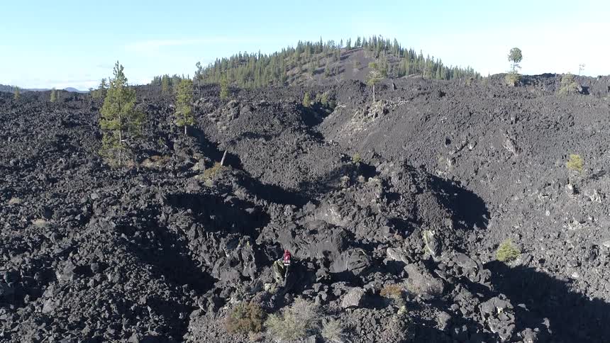 Person climbs up a dirt mountain under blue skies