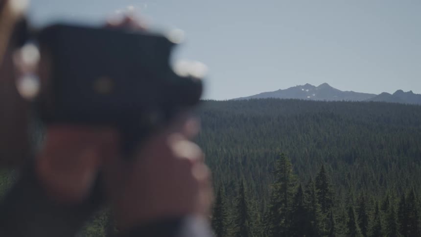 Man standing on a hill makes a video of the dense forest