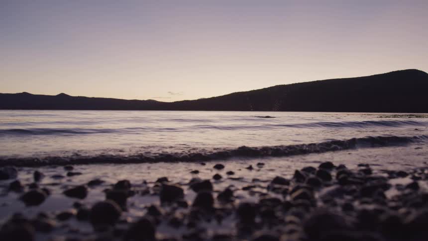 Waves gently lapping on lake shoreline at sunrise