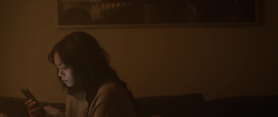 A woman is looking at her phone in a dark room