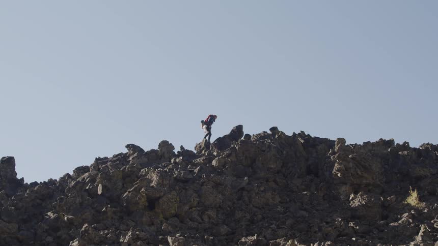 A person is hiking and jumping over the rocks on the mountain