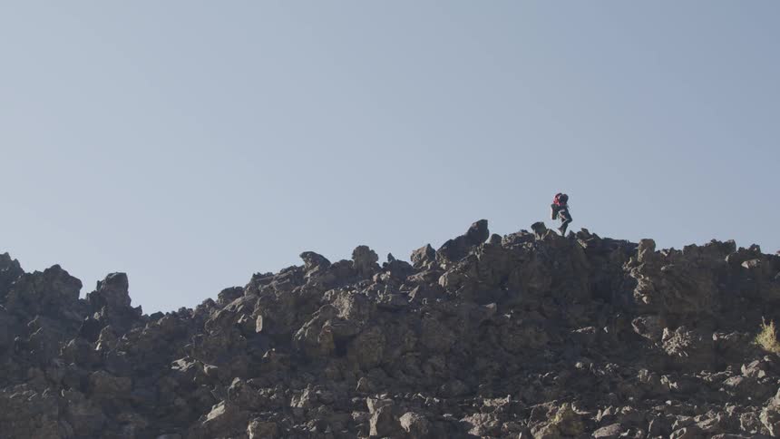 A teenager hikes across a large pile of rocks