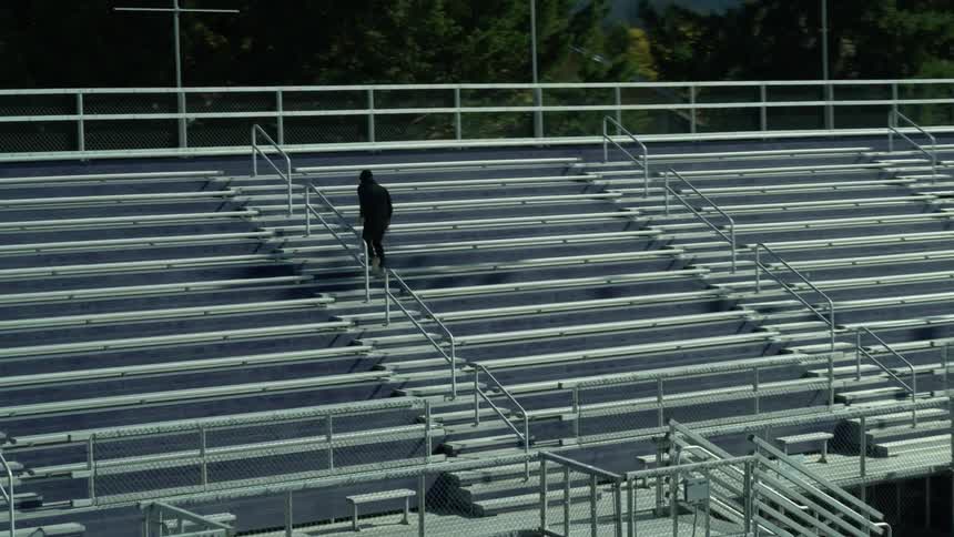 A man runs up a set of outdoor metal bleacher stairs