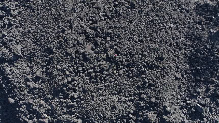 A hiker walking across a rocky gray landscape devoid of vegetation