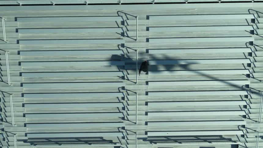 Man runs up the steps near the bleachers under the bright sun