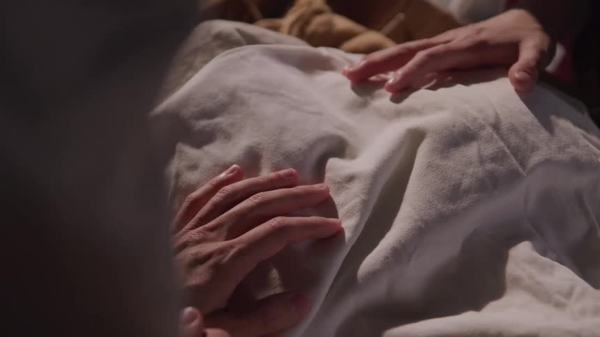A woman has her hands on someone while they sleep
