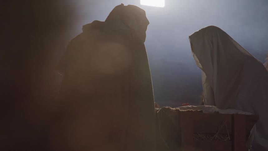 Actors portraying mary and joseph looking down at baby jesus in the manger