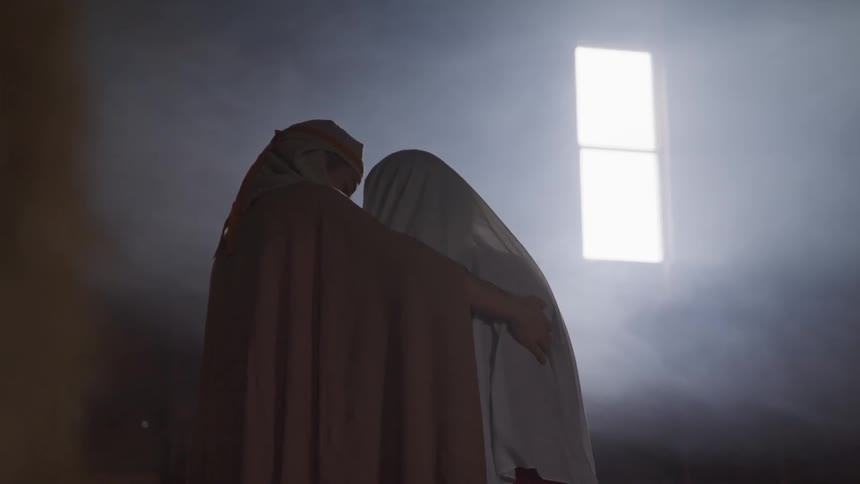 A woman in a robe hugs another person