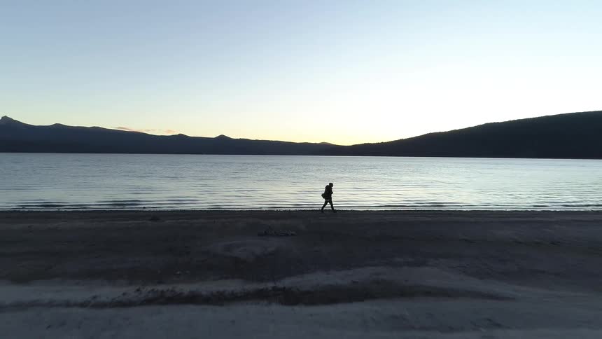 Man walks along the lakeside at dawn