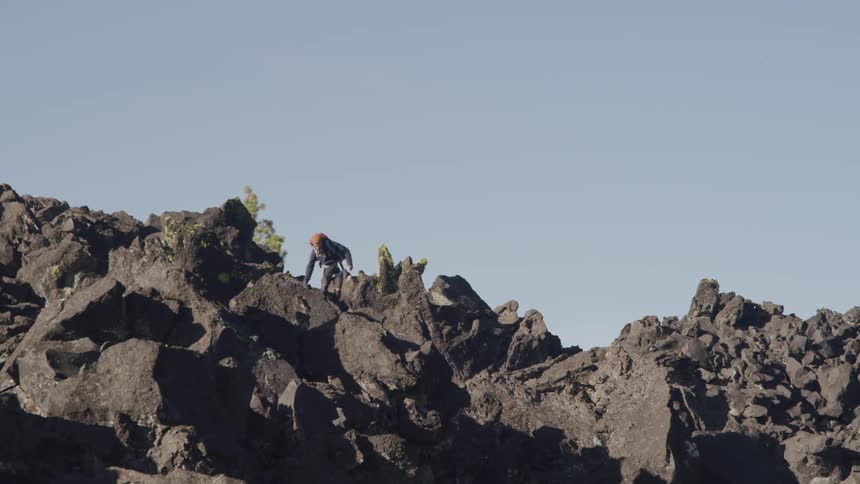 A person hiking on rocky terrain with the sky in the background