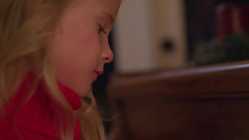Blonde girl wearing a red turtle neck shirt plays the piano