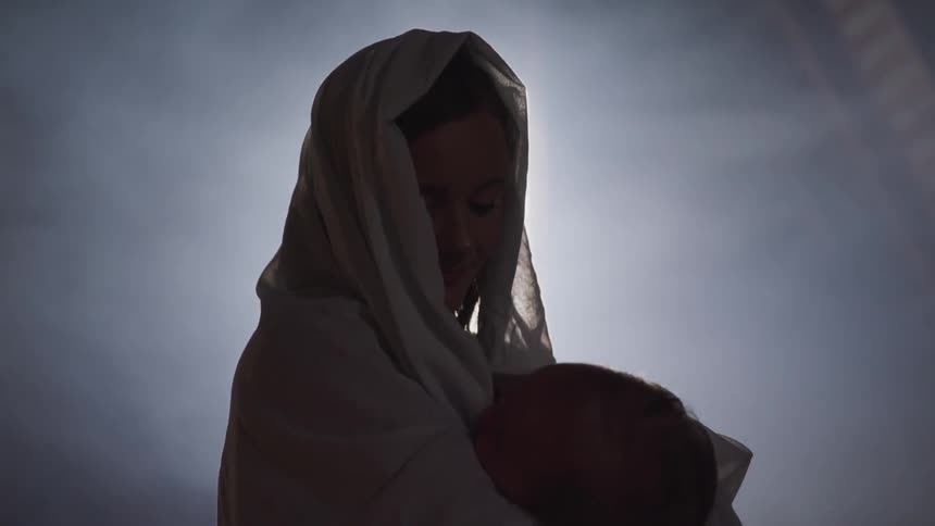 A woman cradles her child in the dark room