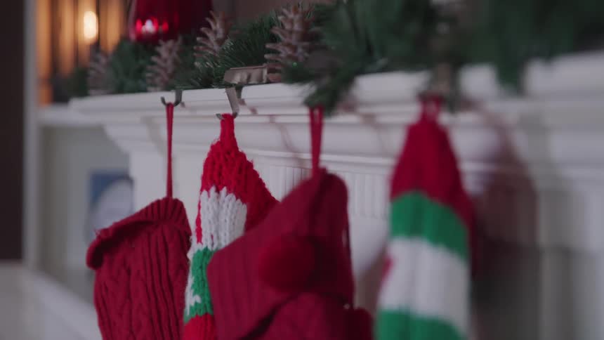 Four christmas stockings hang on the decorated mantle