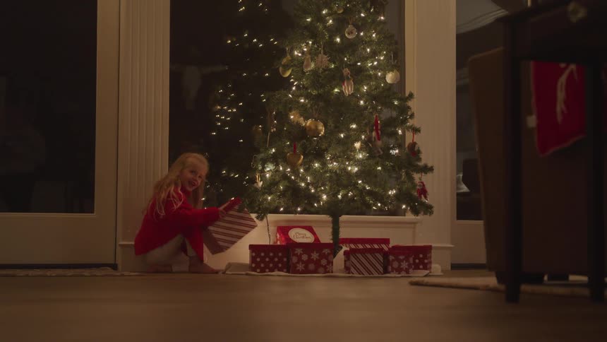 Girl rushing to open the gifts under christmas tree
