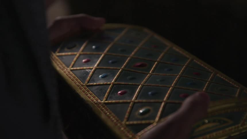A man holds a small box decorated with jewels in his hands