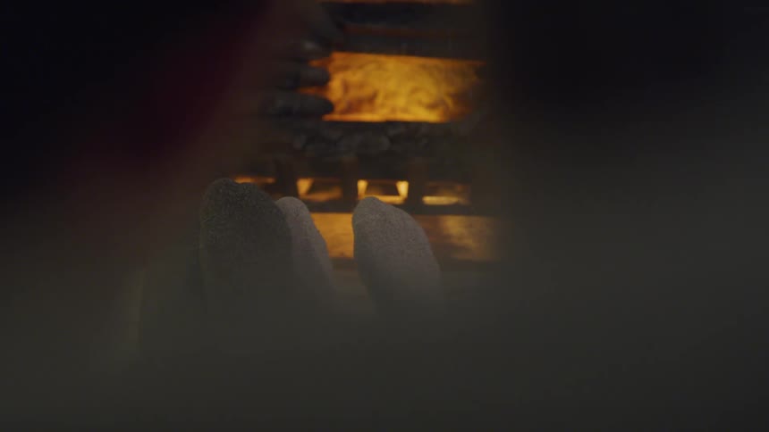 Man and woman sitting on the floor warms their feet in the living room at home
