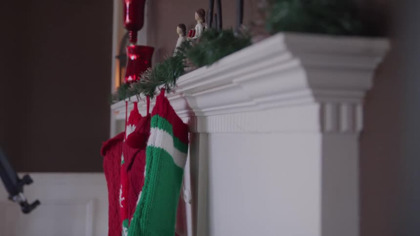 The fireplace in a home is decorated with stockings and garlandfor christmas