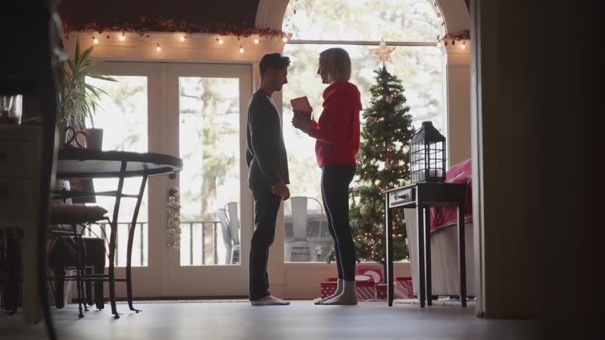 A man giving a gift to a woman and she hugs him afterwards