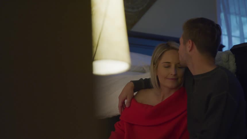 Couple sitting at home while romantically hugging and kissing