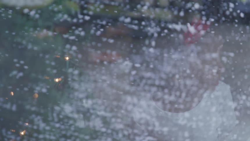 Little girl looks out the window while the snow falls