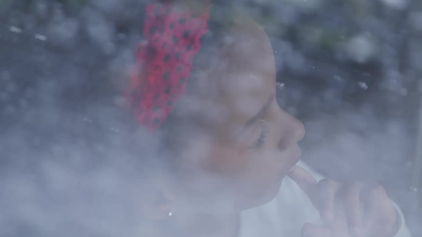 Black girl looking to the snow outside through the window