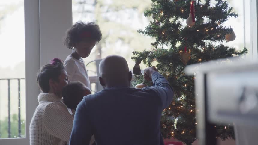 Black family enjoying christmas indoor next to a christmas tree