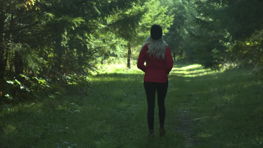A woman walks along a path in the middle of trees