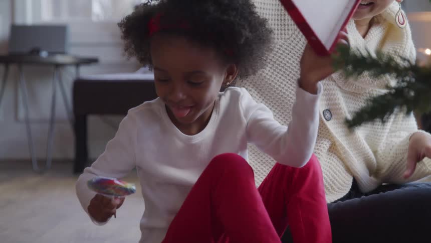 A young girl opens a box and pulls out a colorful lollipop