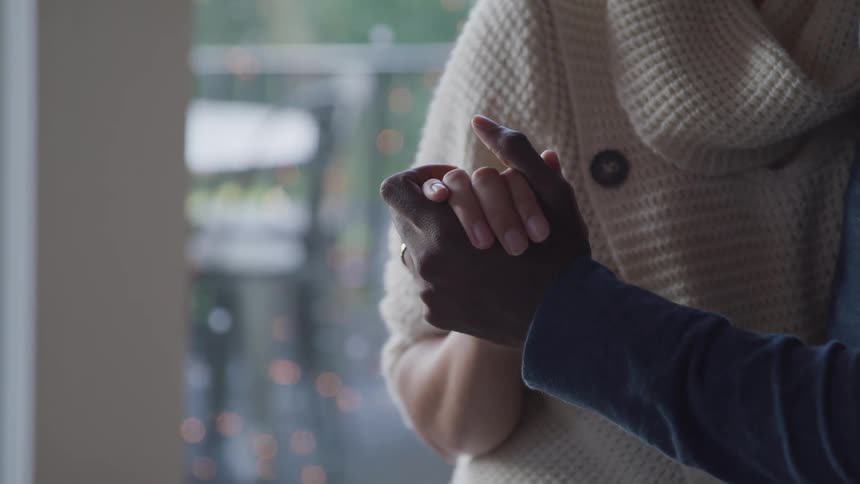 Man and woman dance in each others arms near glass doors looking out onto patio