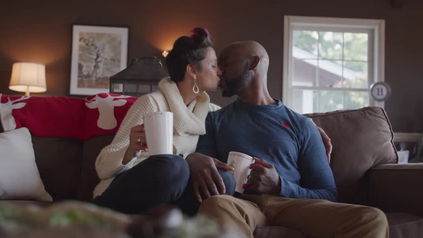 Husband and wife sitting on the sofa kiss each other in the living room
